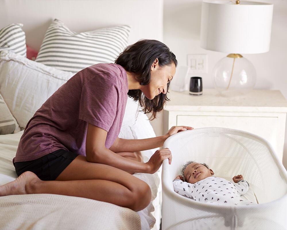 maman qui regarde son bébé dans un lit cododo pret du lit