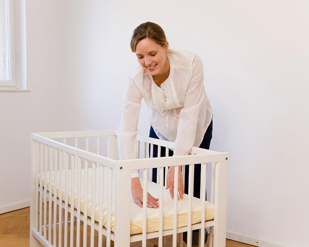 maman qui touche le matelas dun lit a barreaux