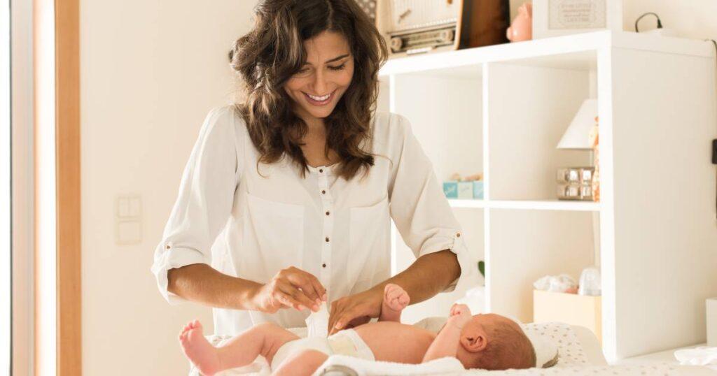 quel lit parapluie choisir : maman change son bébé sur une table à langer